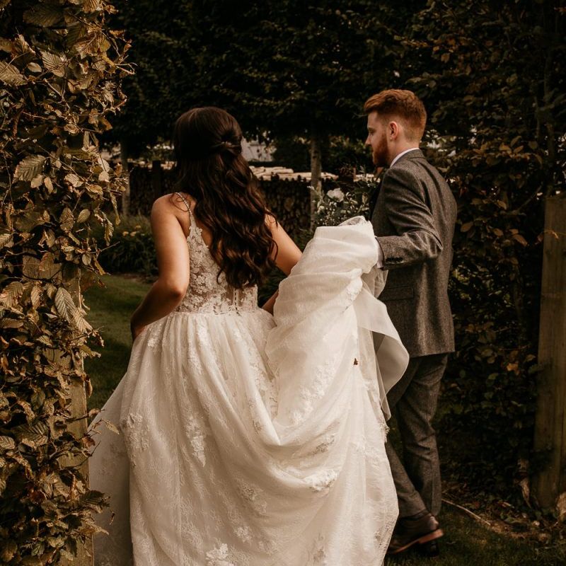 Groom helping his bride with her wedding dress train