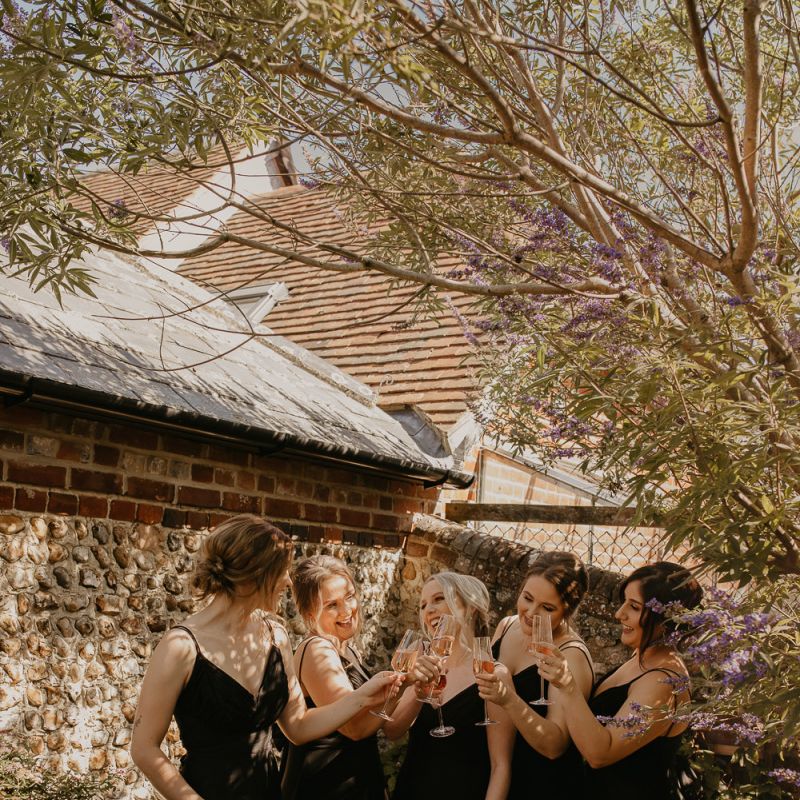 Bridesmaids in black dresses raising a toast