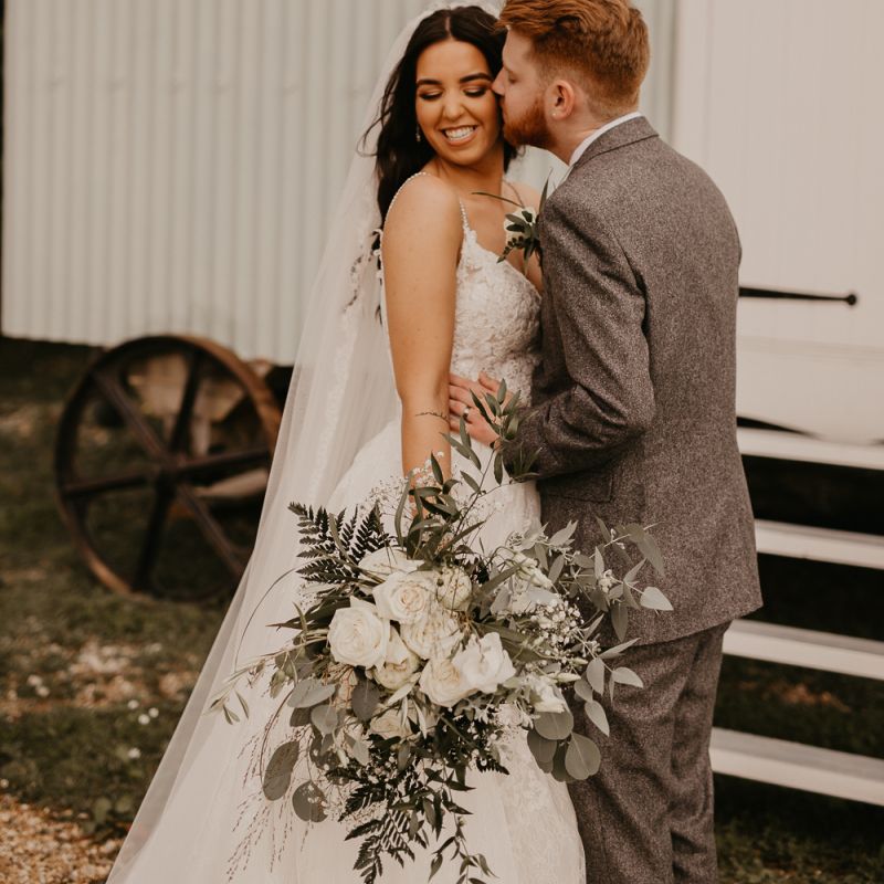 Groom kissing his bride in a Enzoani wedding dress
