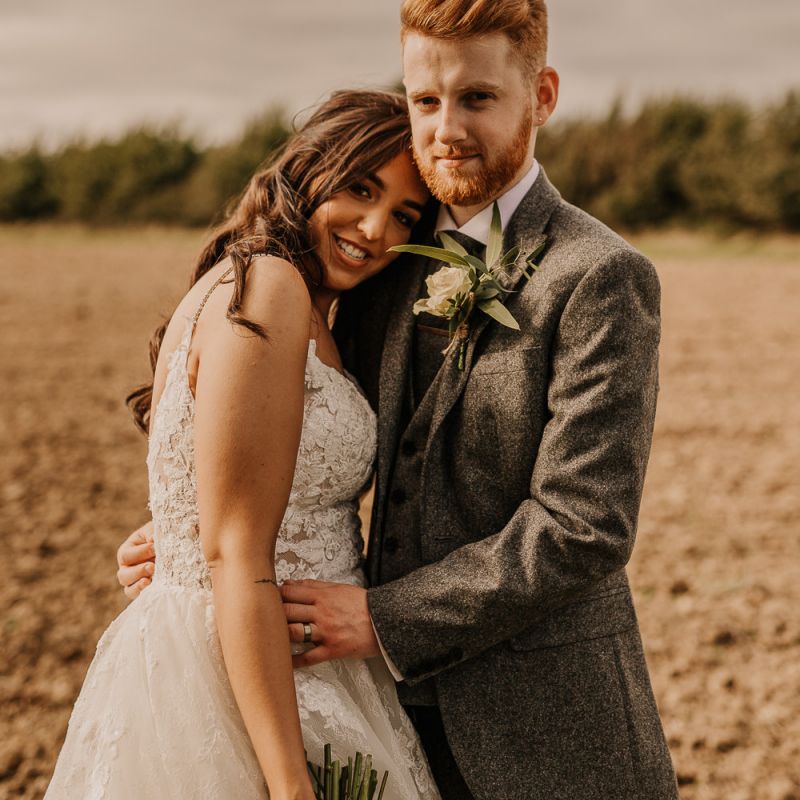 Bride and groom embracing on the field