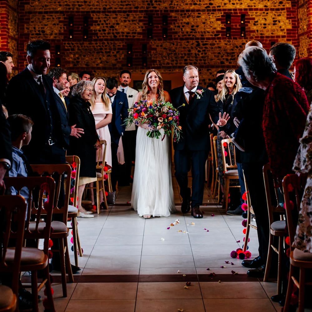 Wedding Ceremony | Bridal Entrance in Red &amp; White Joanne Fleming Design Wedding Dress | Colourful Alternative Winter Wedding at Upwaltham Barns, Sussex | Epic Love Story Photography