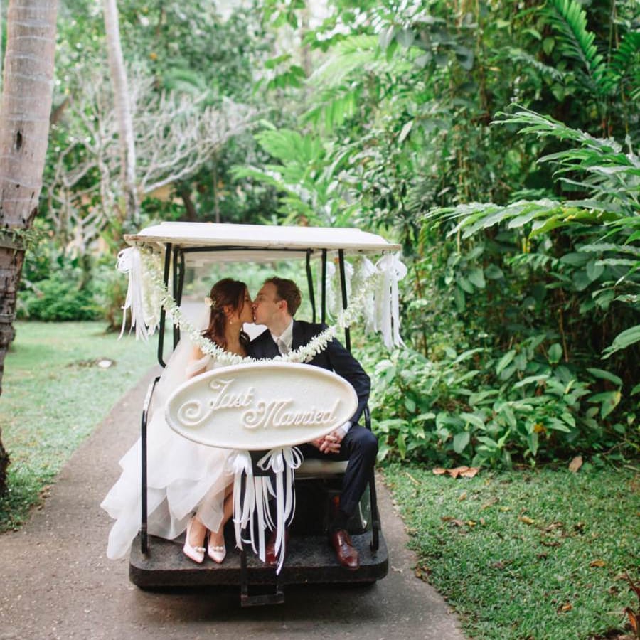 Bride and groom on a gold buggy at a Tropical wedding