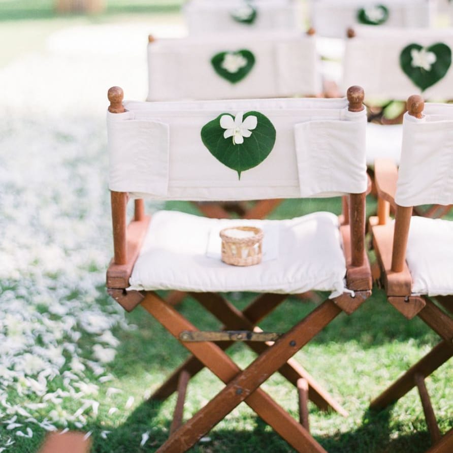 White director chairs with tropical wedding flowers on the back
