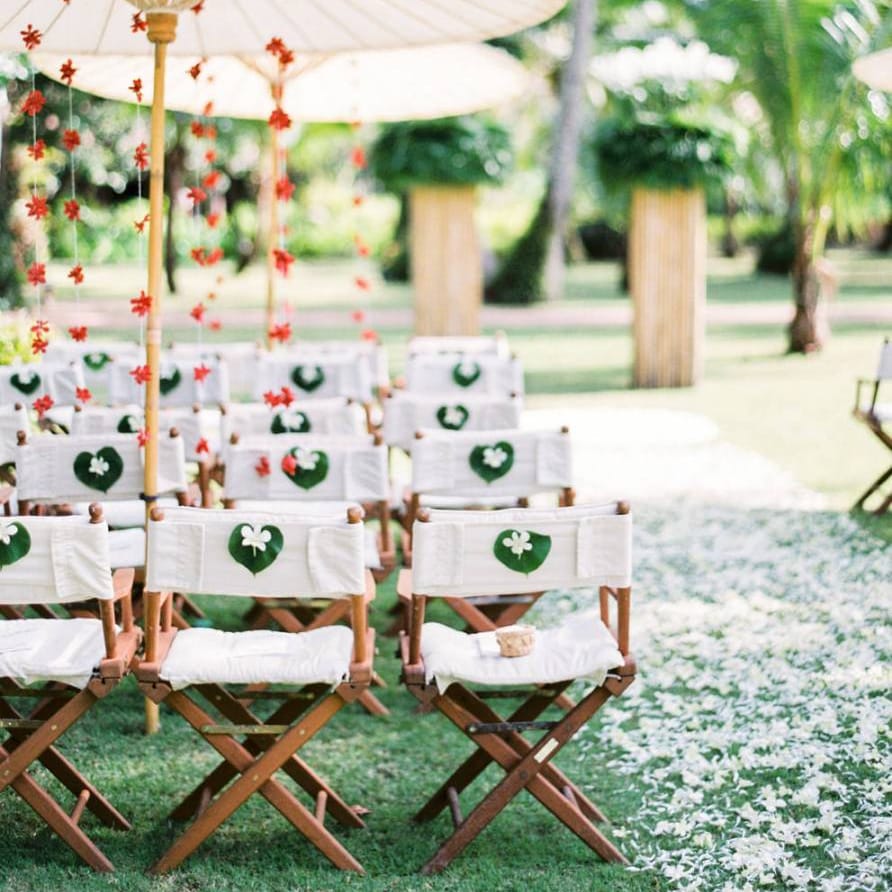 Outdoor tropical wedding decor with director chairs and parasols