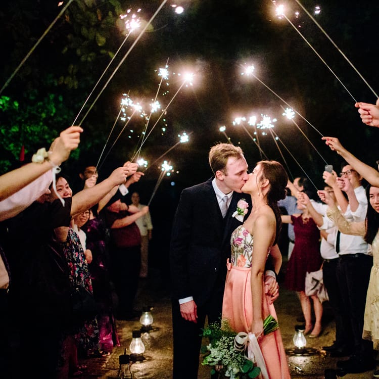 Sparkler moment at tropical wedding with bride in pink second wedding dress