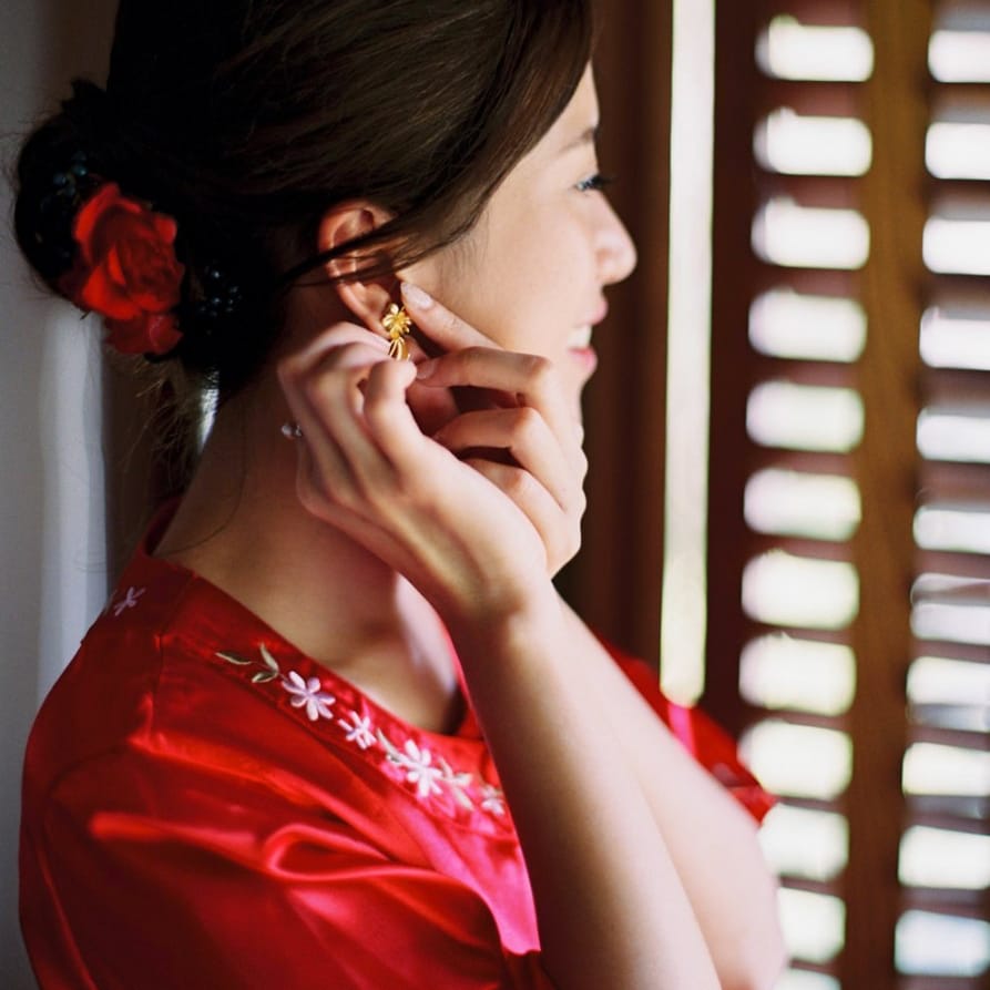 Bride in red getting ready robe putting on her earrings