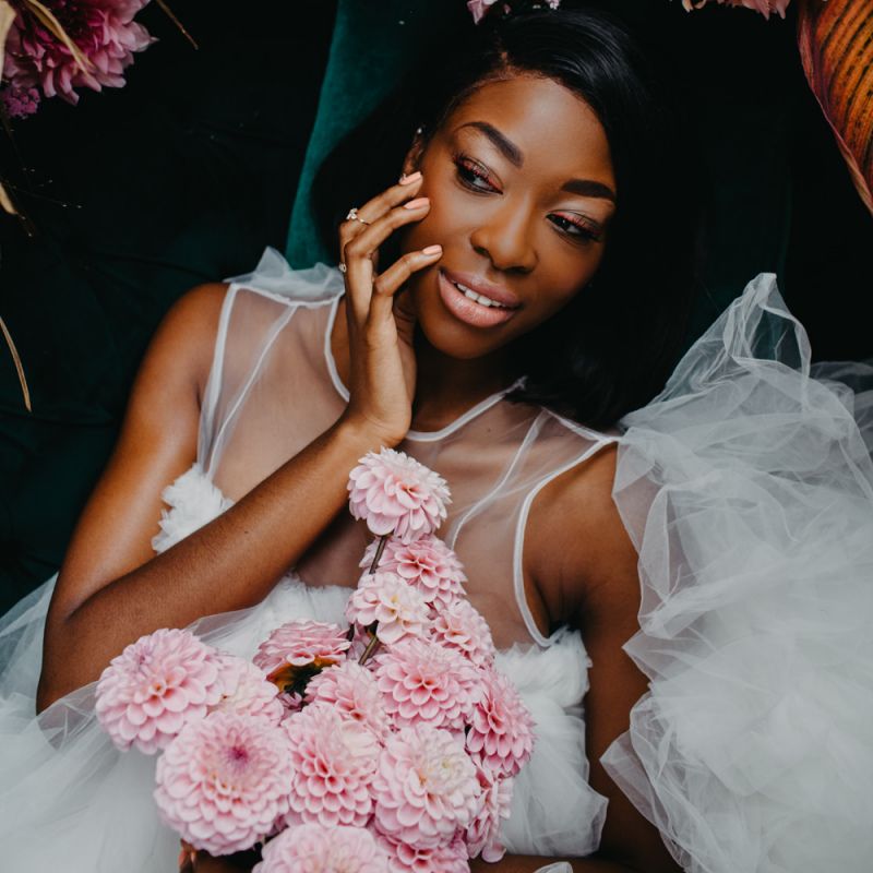 Bride with illusion neckline wedding dress holding a pompom bouquet