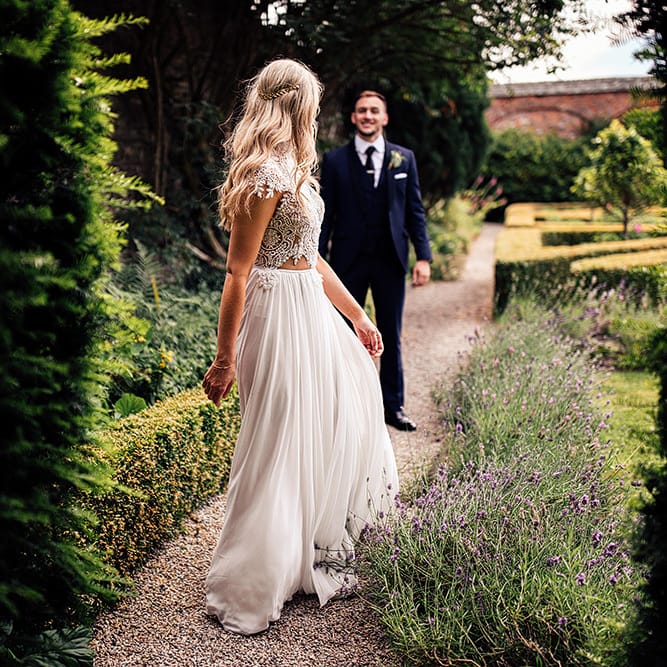 Bride in Julio Vino wedding dress walking through the gardens at Kingston Estate, Devon