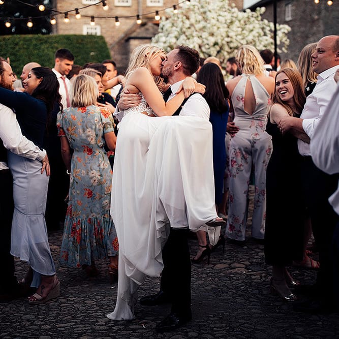 Groom picking up his bride during outdoor wedding first dance