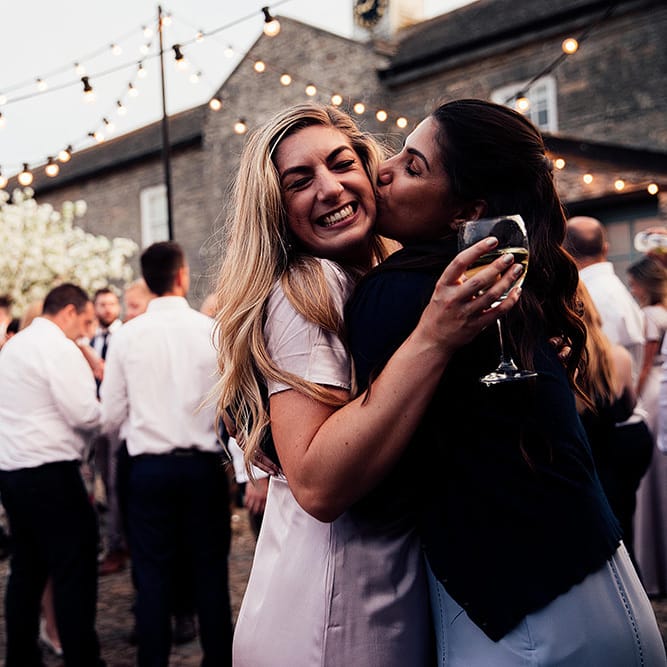 Wedding guests hugging at outdoor evening reception
