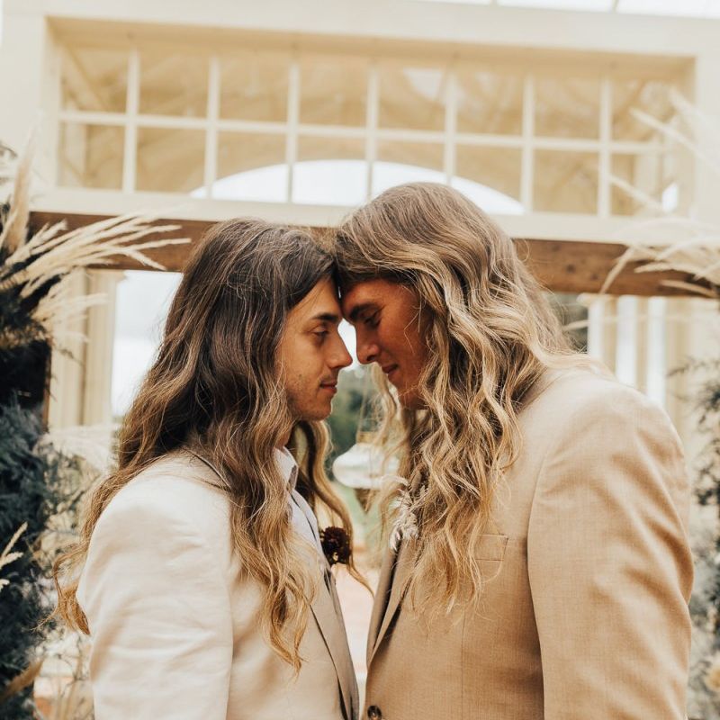 Two grooms in beige suits and long wavy hair