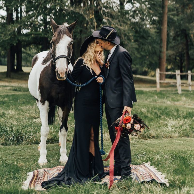 Bride and groom kissing next to a horse