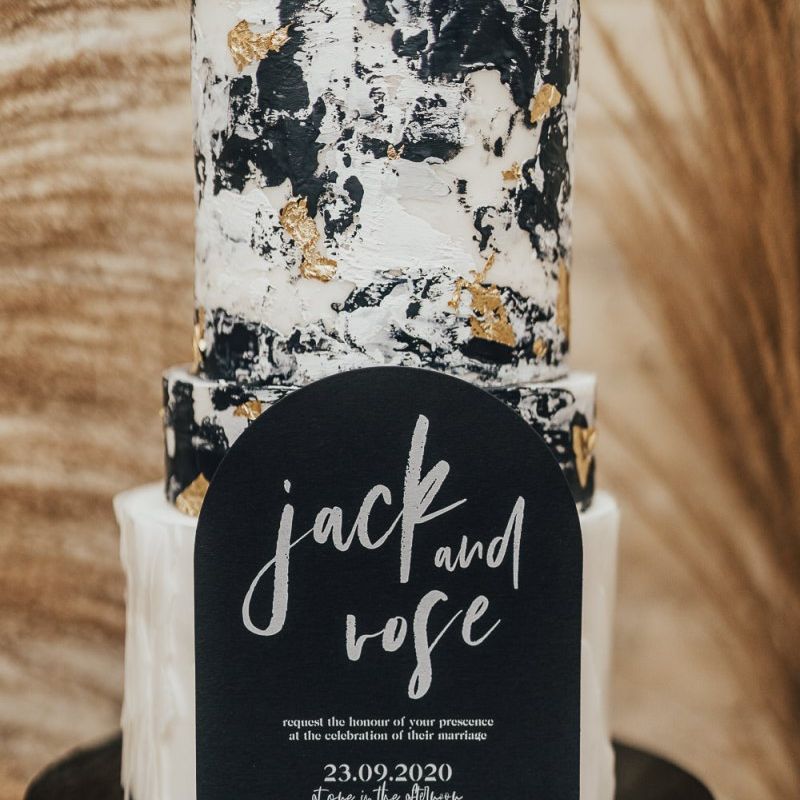 Black wedding invitation in front of night sky wedding cake