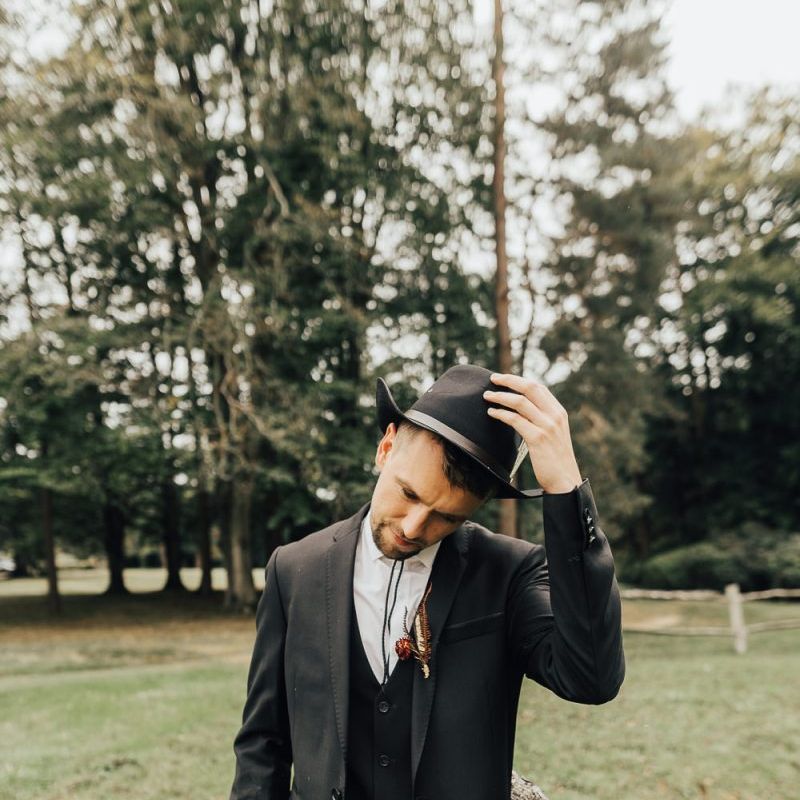 Groom in black hat and bootlace tie for western wedding