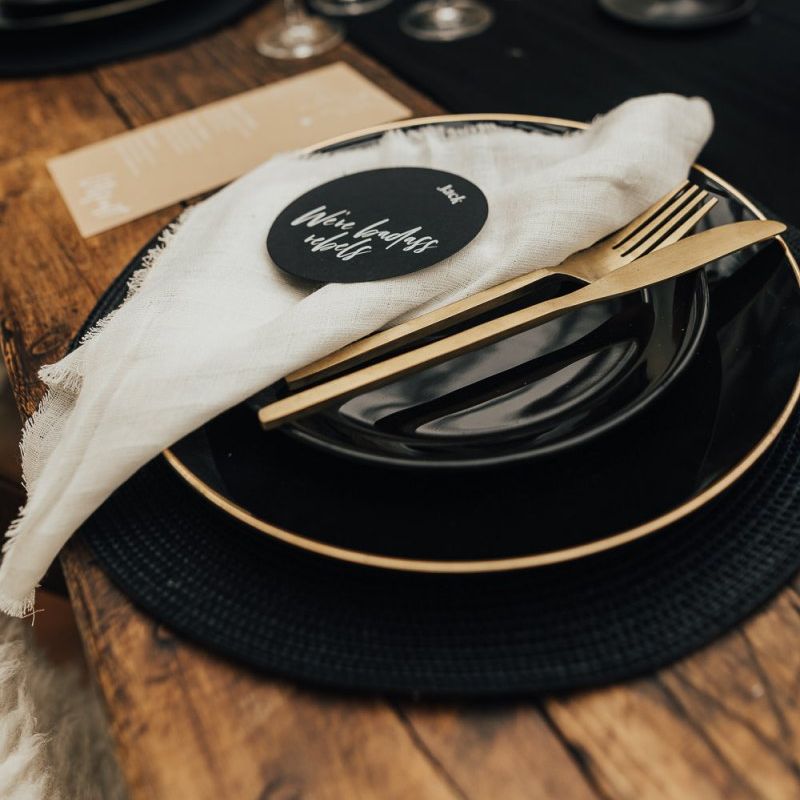 Place setting with black tableware and gold cutlery