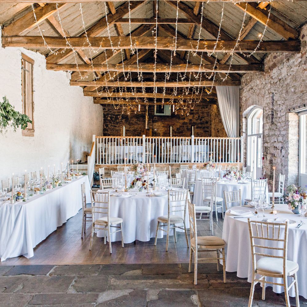 Barn Wedding Reception Decor with Exposed Brick and Fairy Lights Hanging From The Rafters