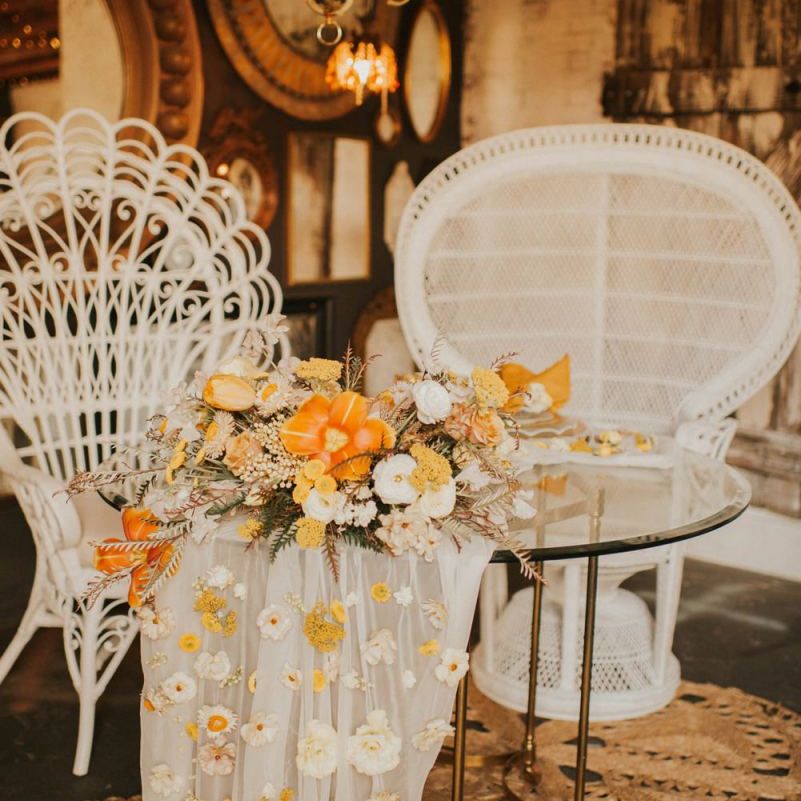 Sweetheart table with peacock chairs and orange bridal bouquet