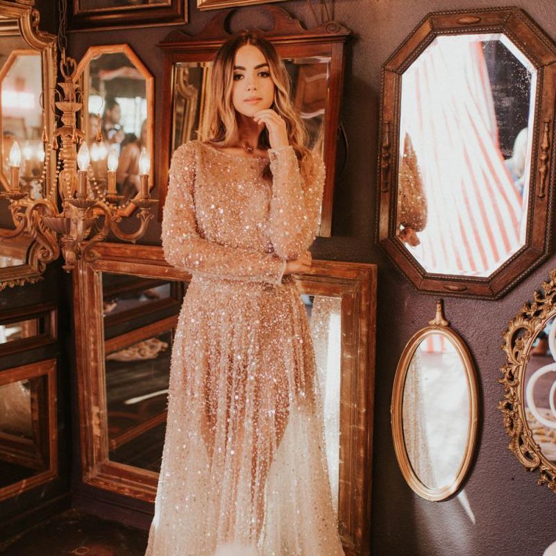 Boho bride in sparkly wedding dress standing in front of ornate mirrors
