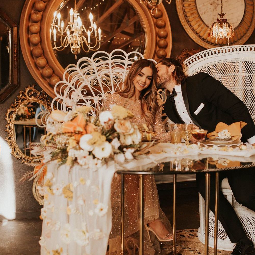 Bride and groom sitting at sweetheart table in peacock chairs