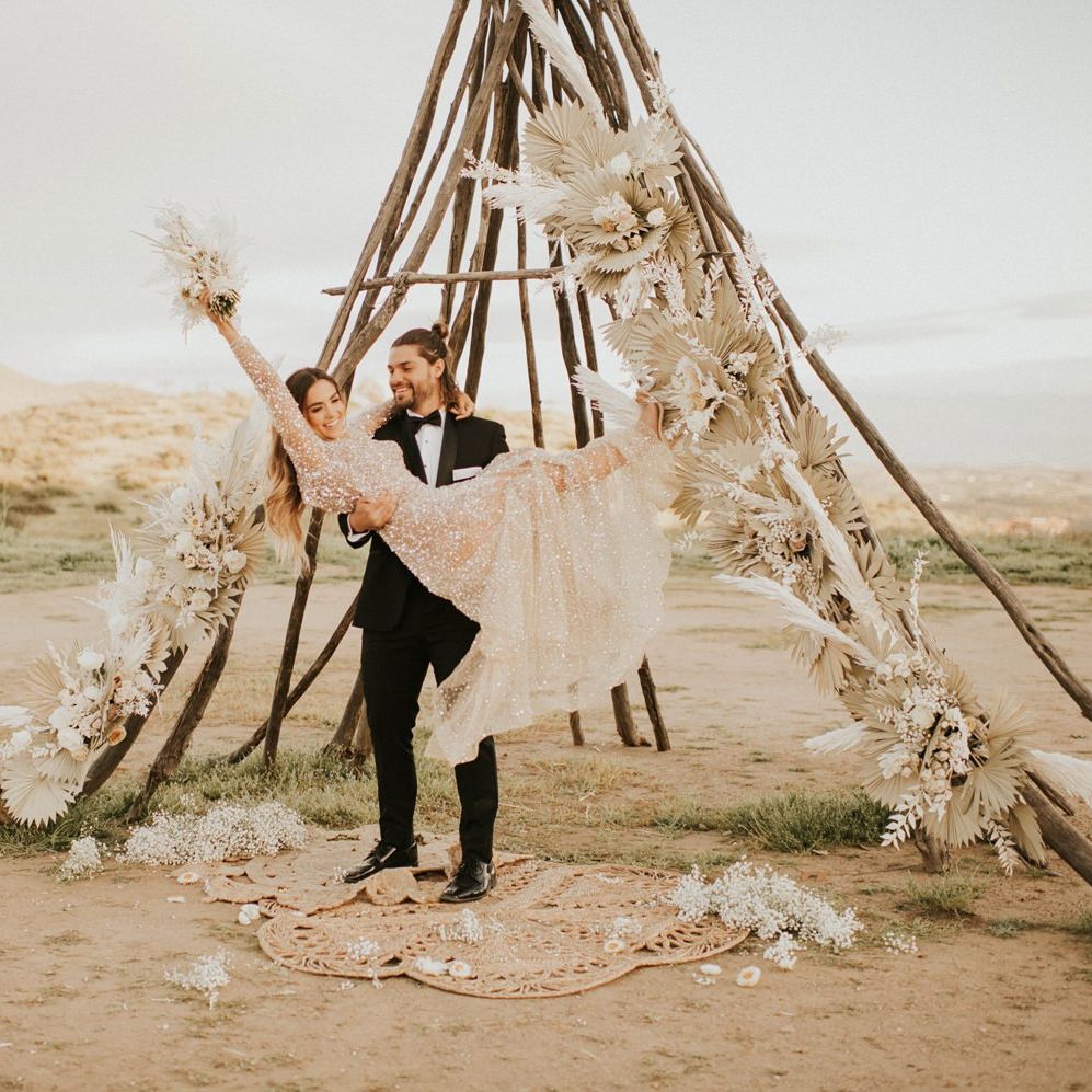 Groom in tuxedo picking up his bride