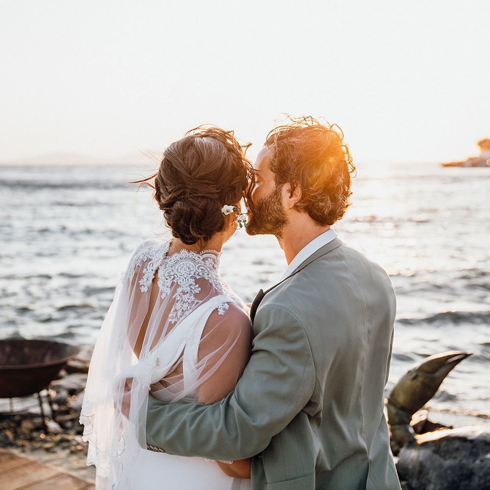 Groom kisses bride in wedding capelet at Mykonos wedding
