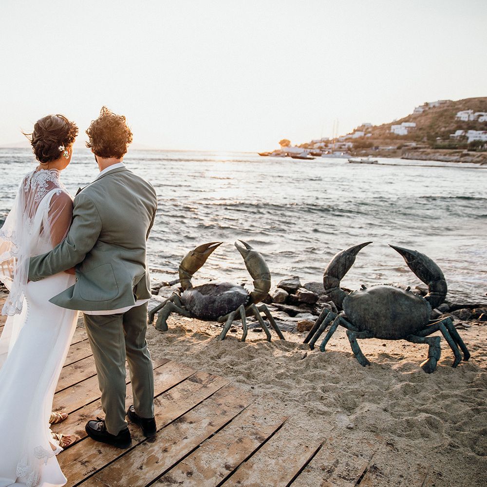 Bride in wedding capelet with groom overlooking the beautiful views at Mykonos wedding