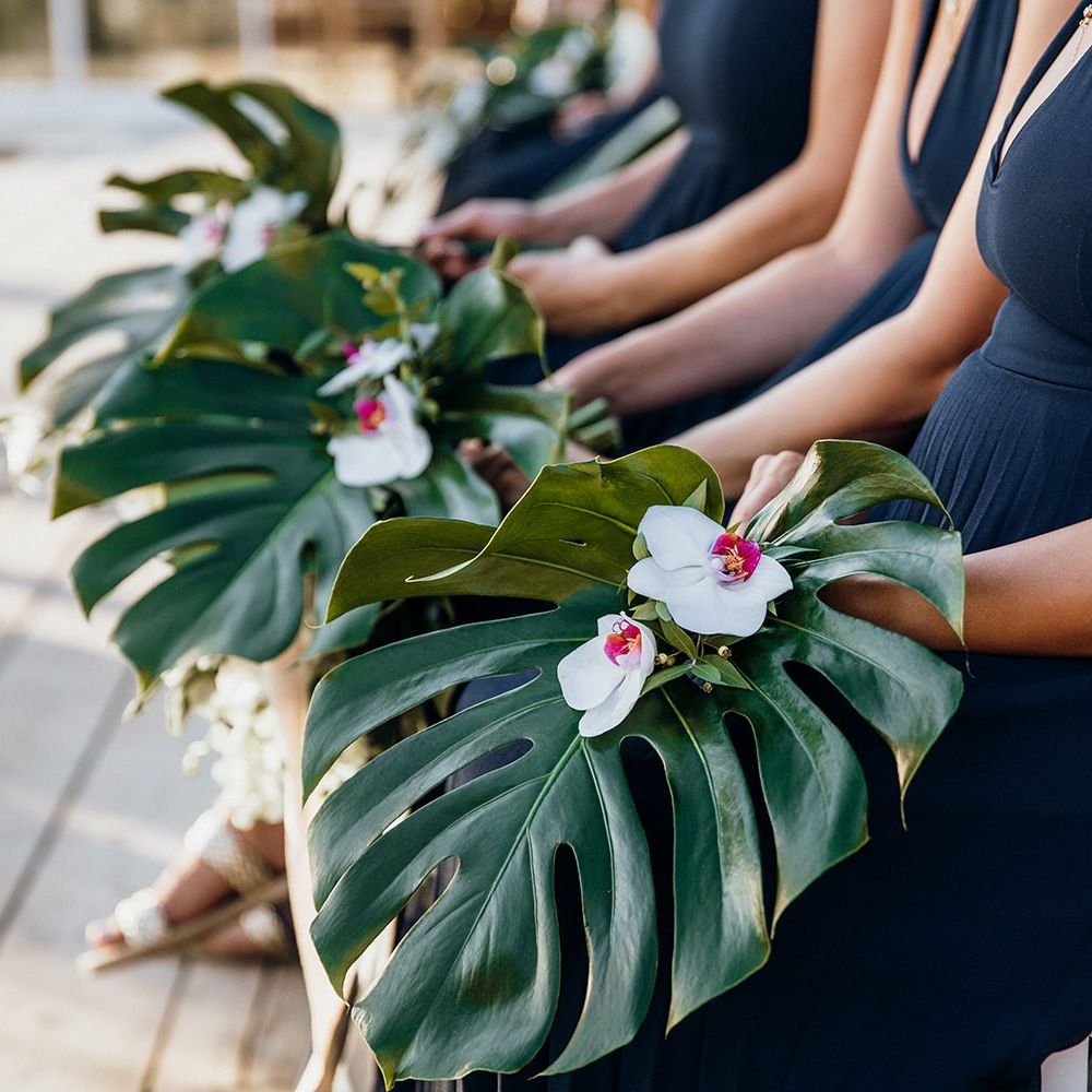 Bridesmaid hold palm leaves as alternative bouquets