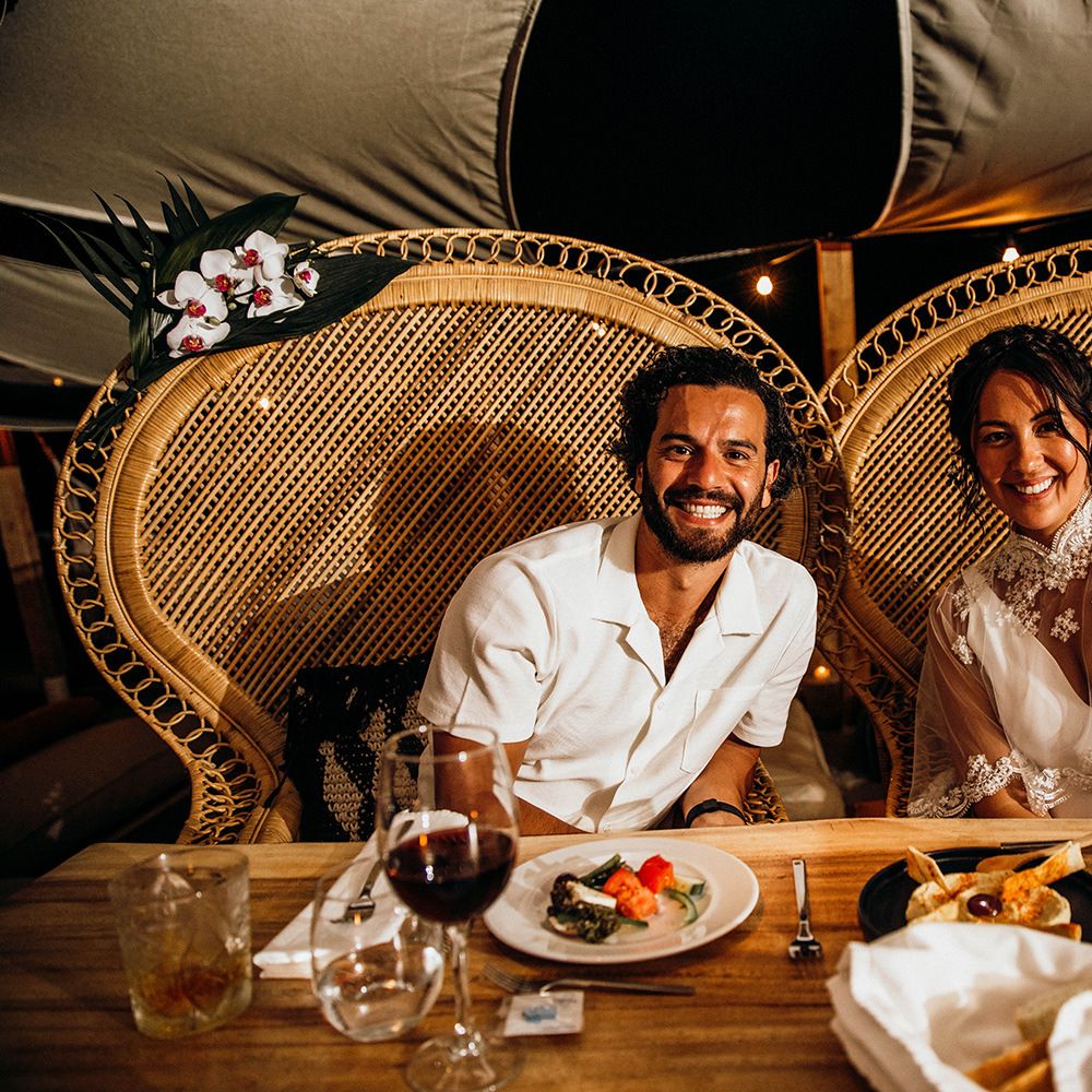 Bride and groom sit on peacock chairs during wedding breakfast