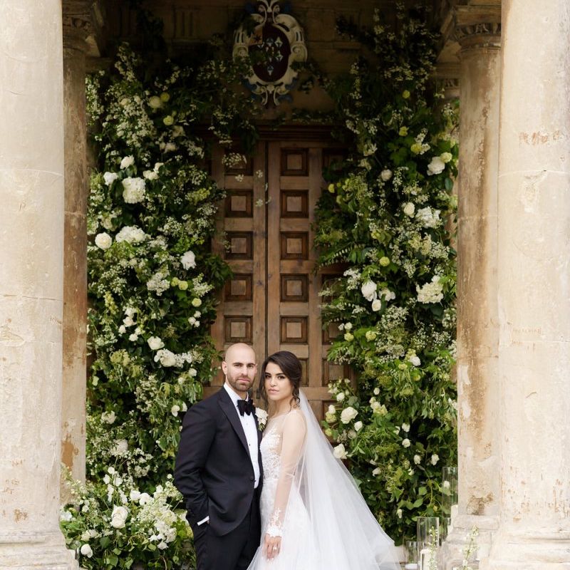 Bride and Groom Portrait by a Large White and Green Floral Arrangement
