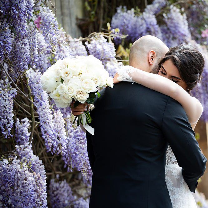 Bride Embracing Her Groom Holding an All White Rose Wedding Bouquet