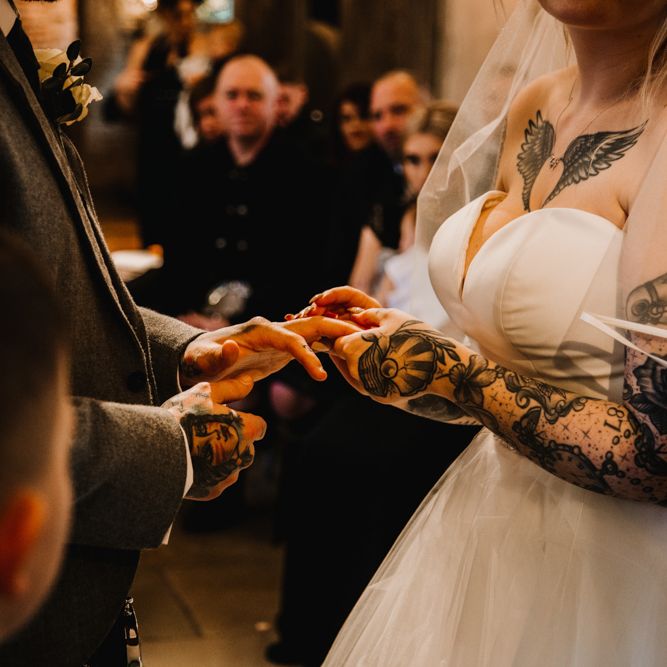 Tattooed Bride in Off The Shoulder Wedding Dress Holding Hands with Her Groom at the Wedding Ceremony