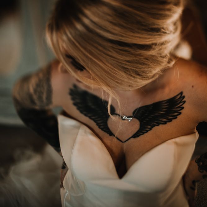 Tattooed Bride in Sweetheart Neckline Wedding Dress Showing Off Her Heart and Wings Ink