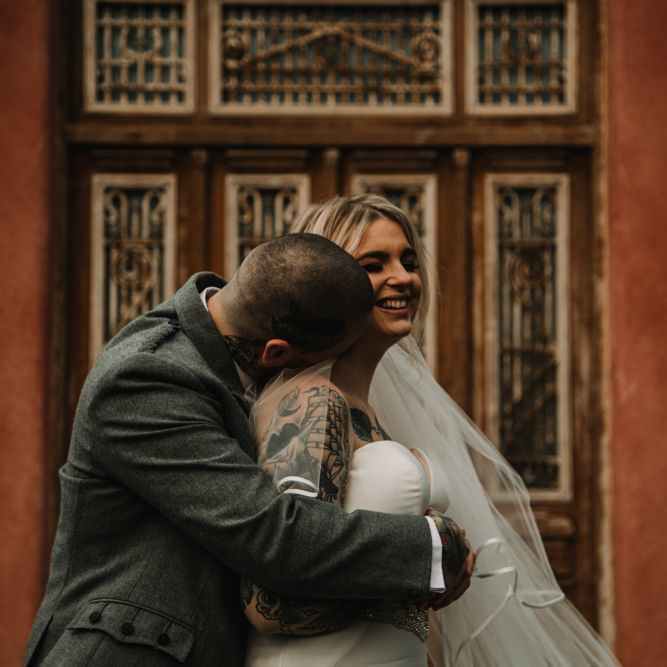 Bride in Fishtail Essense of Australia Wedding Dress and Groom in Tartan Kilt Embracing