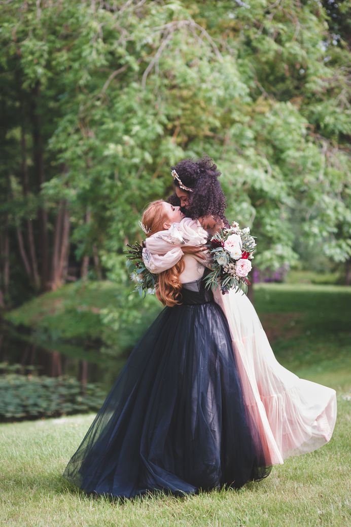 Two brides embracing at autism marriage diverse wedding inspiration. Brides wear coloured wedding dresses and pretty hair accessories
