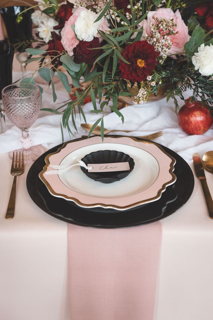 Wedding table decor with black charger plate, pink and gold tableware and floral centrepiece 