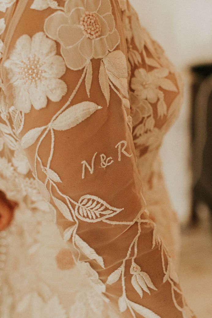 Bride in wedding dress with long sheer sleeves with embroidered roses and embroidered initials