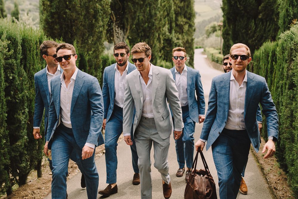 Groomsmen wearing coordinated suits, standing in an outdoor ceremony backdrop