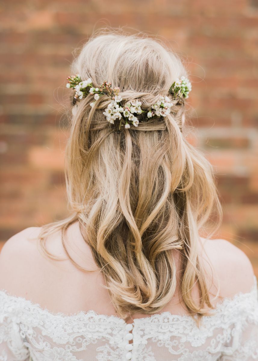 Brunette bride wears low bridal updo with white flower hair accessory