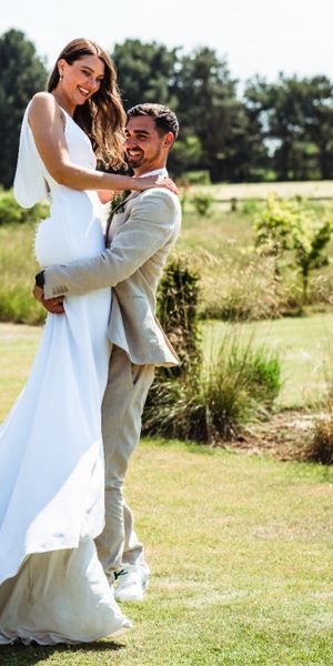 Groom picking up his bride on heir wedding day at Oakwood at Ryther. They are being playful and smiling. 