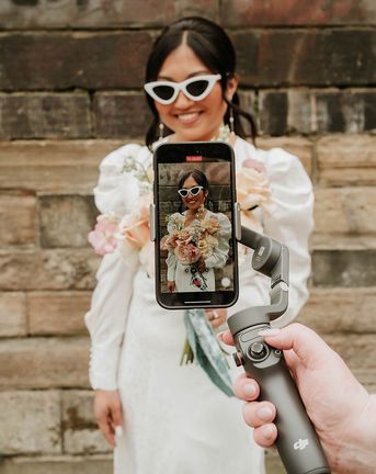 Wedding content creator filming bride with retro sunglasses on