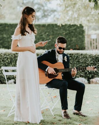 Bridesmaid gives a wedding reading during a ceremony with guitar player.