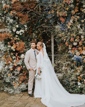 Bride and groom in front of large floral display at Sezincote House.