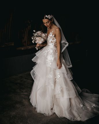 Bride in a layered tulle Wtoo by Watters wedding dress and flower hairpiece.
