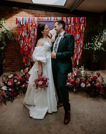 DIY rainbow streamers altar decoration with bride and groom