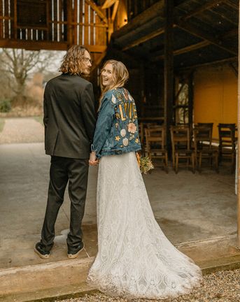 Groom in black tie with bride in lace Rosa Clara dress and bespoke embroidered denim jacket. 