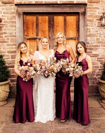 Bride in Emmy Mae bridal gown and bridesmaids in burgundy satin bridesmaid dresses.