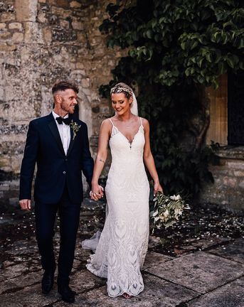 Bride in lace wedding dress and groom in black tie walk together at Athelhampton House.