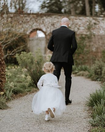 Flower girl in a white dress and cardigan to play a role in a wedding