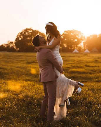 bride is lifted up by the groom for their golden hour wedding photos