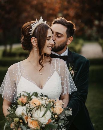 Bride in a dotted wedding dress and quartz crystal crown with the groom in a velvet suit jacket.